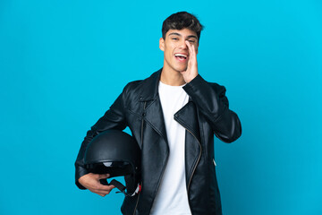 Young man with a motorcycle helmet over isolated blue background shouting with mouth wide open