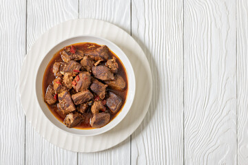 beef stew in a white bowl on rustic wooden table
