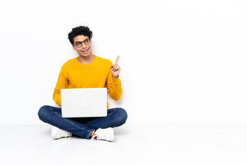 Venezuelan man sitting on the floor with laptop pointing up a great idea