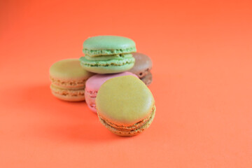 Macarons stacked, isolated, on orange background and copy space.