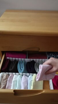 A woman's hand takes out the linen from the dresser drawer. The concept of order, storage and organization of space.