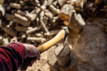 A first-person perspective of a person splitting firewood with an axe. 