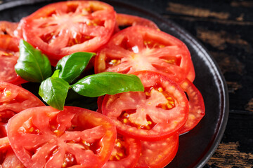 Organic Tomato Slices and Basil Leaves on Black Plate, Italian and Mediterranean Cuisine, Close-Up