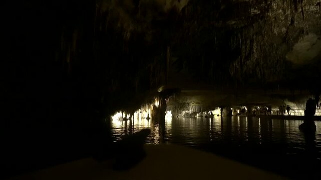 Tourists enjoying a boat trip in the illuminated drach caves of mallorca, surrounded by stunning rock formations and reflections