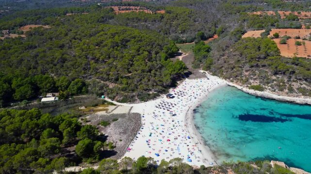 Aerial view of tourists enjoying the white sand beaches and turquoise water of a cove in mallorca