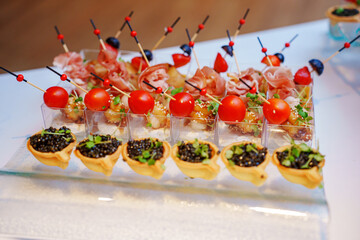 different canapes in cups with sauce and tartlets with black caviar. Convenient and beautiful serving of appetizers at a buffet table. catering at events.