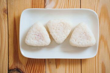 Onigiri made of rice are spun on a white plate. A simple and delicious Asian snack meal.