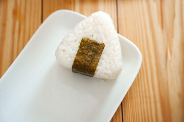 Onigiri made of rice and nori seaweed are spun on a white plate. A simple and delicious Asian snack...