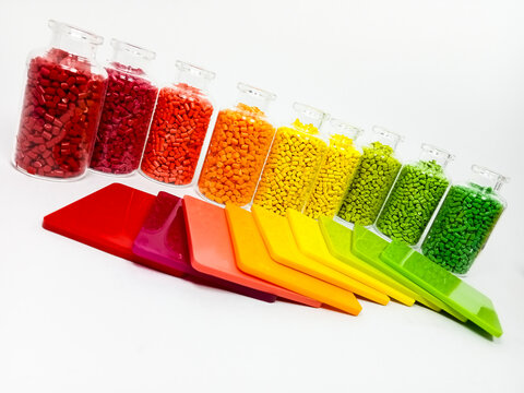various colors of mastebatch granules in glass container with chips, colorful pigment virgin resin, isolated on white background, suitable for plastic industry company profile product catalog design