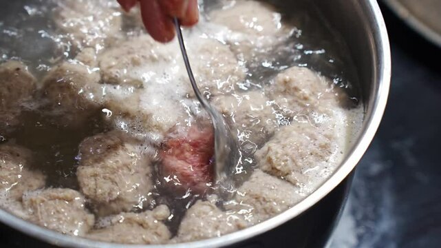 With the help of a spoon, meatballs are made from minced meat and dipped in boiling water. Life hack for the kitchen. Cooking soup with meatballs.