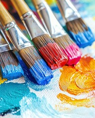 Fototapeta premium Close-up of vibrant paintbrushes dipped in colorful acrylic paints on a textured canvas.