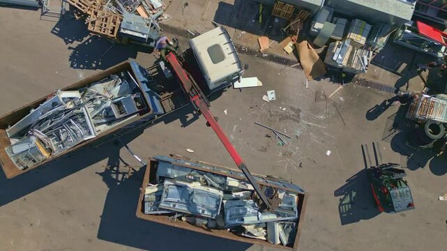 Aerial view of industrial scrap metal recycling with a crane loading metal into containers at a scrapyard. Concept of recycling, sustainability, and waste management in industrial settings