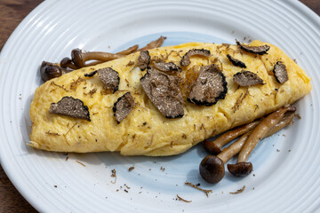 French omelette with mushrooms, fresh farmers eggs and black summer truffle mushroom in pieces for making truffle dishes with tasty aroma