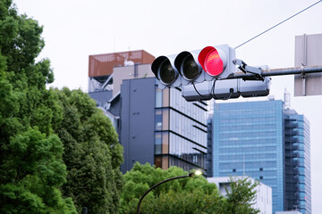 traffic light showing red signal against overcast blue sky in Tokyo, Japan