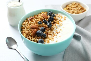 Delicious granola with berries and yogurt on a light background