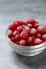 Frozen cranberries in a bowl on a gray background