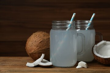 Mason jars with coconut water with nuts on wooden table