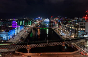 Aerial view of Dublin city center at night during Christmas, with motion blur of people, traffic, and train