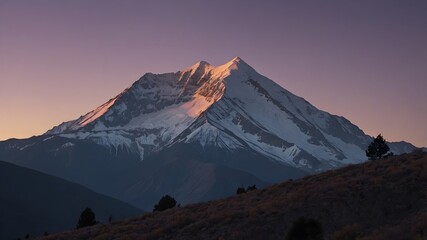 Fototapeta premium A peaceful sunset wallpaper casting a soft glow on the snow-covered peak, contrasting with the dark foothills and creating a serene nature background