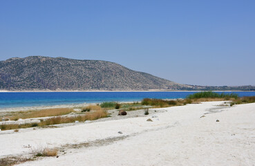 a beach with a body of water and a mountain in the background 
