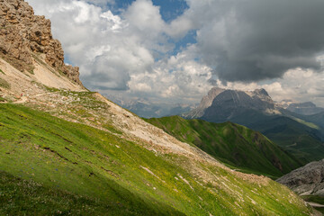 Obraz premium Hiking trail towards Tierser alpl ( Rifugio Alpe di Tires) ,summer day with sun and dark stormy clougs. Beautiful hiking spot in the Italian Dolomites. Impressive mountains in the background.