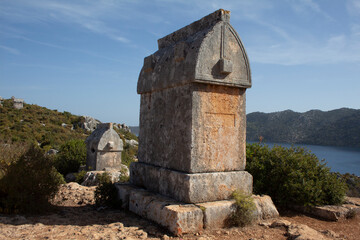 close up Lycian sarcophagus or stone coffins with the sea  and island in the background in Turkey