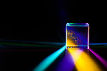A glass dichroic prism disperse light into different colors on a black background