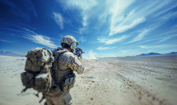 un soldat en train de viser, vu de dos, dans un d&eacute;sert ensoleill&eacute; avec ciel bleu