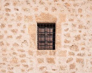 Ancient Spanish stone wall with a metal iron grid window as a prison in Spain to avoid escaping. Pink and orange tones. Concept of freedom and liberty.