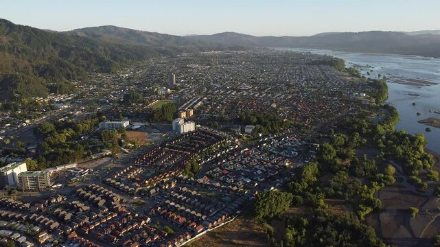 Vuelo sobre ciudad con areas verdes, cerros y rios