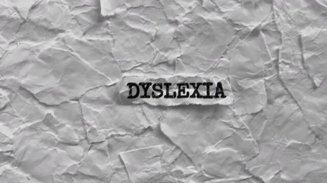 Crumpled piece of paper with word Dyslexia on torn white paper pieces background.