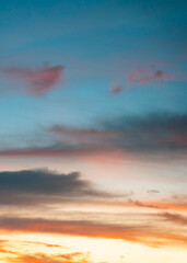 Glowing sunset clouds painted in radiant shades of orange, coral, and pink against a soft blue twilight.