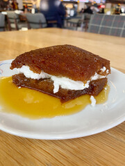 Traditional Turkish dessert ekmek tatlisi with cream. Sweet Turkish dessert ekmek tatlisi with cream served on a plate in a cozy cafe environment