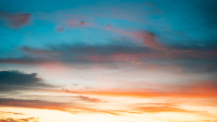 Evening skyscape showcasing soft pink clouds glowing against a luminous blend of blue and orange tones