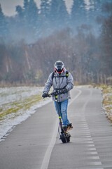 A man rides an electric scooter in the middle of winter