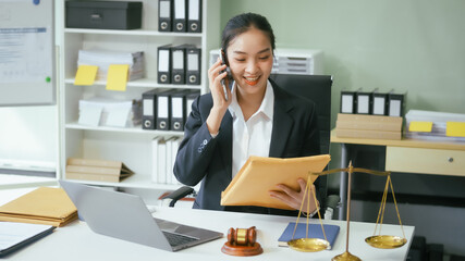An Asian female lawyer sits at her desk in a modern law office, examining documents meticulously....