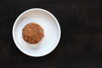 Cat food, pate, top view. Canned food for pets in a round white plate on a dark background. Tasty and healthy food for domestic cats. A portion of wet food, soft pate for a cat on a plate. Copy space