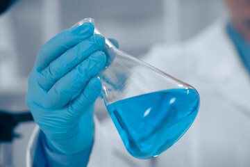 In a wellequipped lab, a passionate scientist holds a vibrant blue liquid in a flask, highlighting...