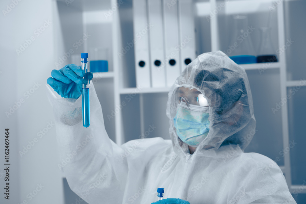 Aufkleber A scientist clad in protective gear is meticulously analyzing a liquid sample contained within a laboratory test tube, demonstrating the critical role of safety and precision in scientific research