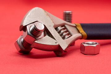 Bolts and nuts with a tool on a red background