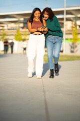 Two friends walking together while looking at a phone