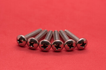 A pile of metal screws on a red background