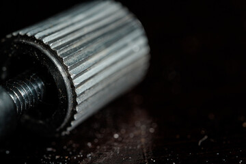 Close-up of a metallic threaded knob with a ribbed texture.  Industrial detail shot.