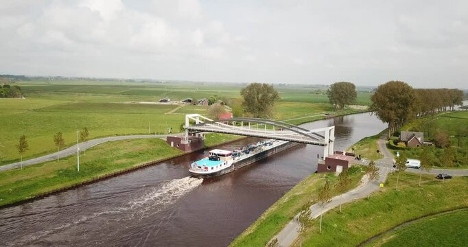 Spring evening. The camera statically captures a white arched railway bridge over a canal. At this time, a train is traveling across the bridge from left to right.