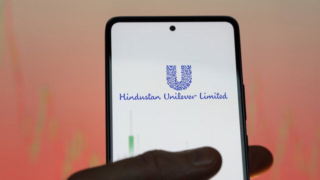 An investor analyzing the hindustan unilever etf fund on a screen. A phone shows the prices of Hindustan Unilever