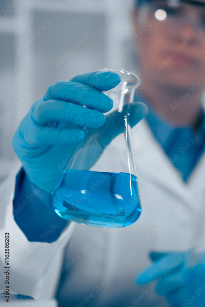 Poster A scientist in a laboratory is holding a flask that contains a blue liquid, demonstrating the rigorous analysis pursued in the fields of biochemistry, chemistry, and related scientific studies