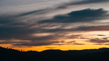 Peaceful sunset showcasing vibrant streaks of gold, peach, and violet across a serene evening sky
