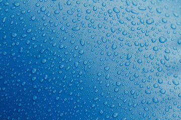 Water droplets on top a textured blue surface.