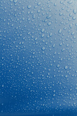 Water droplets on top a textured blue surface.