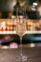 A glass of Prosecco or sparkling wine on the table with blurred bottle display on the background